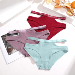 Three pairs of underwear in red, purple, and green with matching straps on a light background.