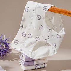 White baby bib with purple floral patterns on a wooden stand against a beige background.