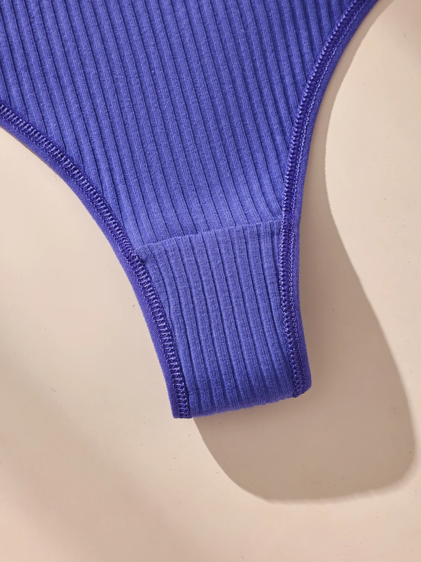 Blue ribbed swimsuit top on a beige background