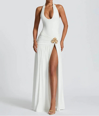 Woman wearing a white halter neck gown with a high slit on a plain background