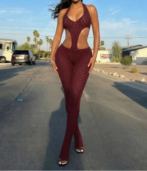 Woman in a burgundy outfit standing on a street with vehicles and buildings in the background
