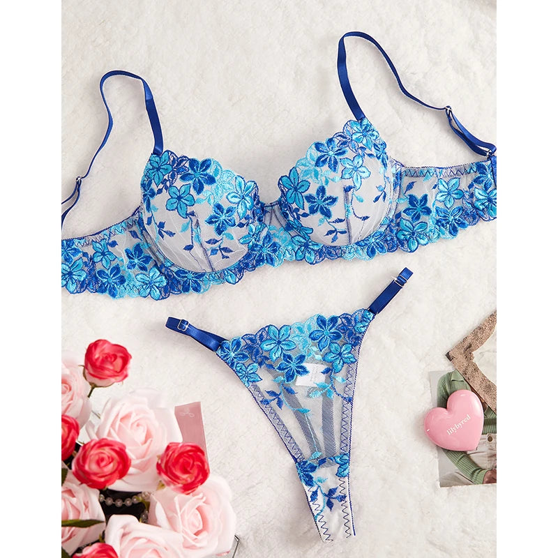 Blue floral lingerie set on a textured white surface with flowers and a heart-shaped object.