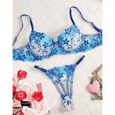 Blue floral lingerie set on a textured white surface with flowers and a heart-shaped object.