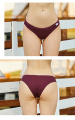 Maroon bikini bottom worn by a person on a blurred outdoor background