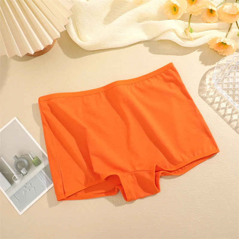 Orange underwear on a beige surface with flowers and a magazine in the background
