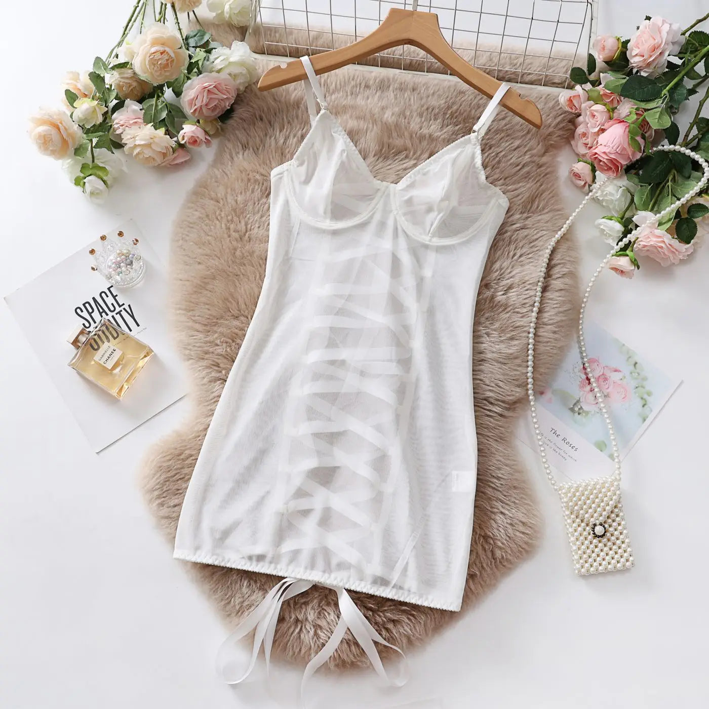 White camisole on a wooden hanger with flowers and a fur rug in the background
