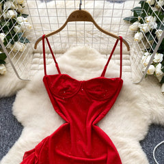 Red velvet dress on a hanger with a white fur rug and floral decorations in the background