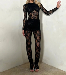 Woman wearing a black lace outfit against a plain background