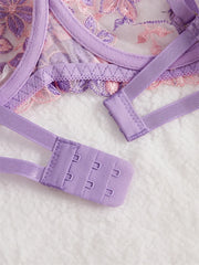 Close-up of a purple lace bra and panties set on a textured white surface