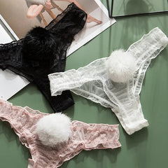 Three pairs of lace-trimmed panties in black, white, and pink on a green surface.