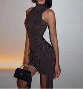 Woman in a brown dress holding a black handbag against a neutral background