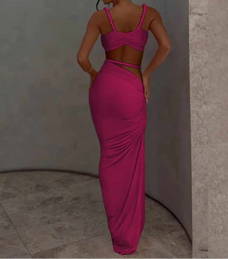 Woman wearing a pink dress with cut-out design against a neutral wall.