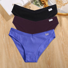 Three pairs of underwear in black, purple, and blue on a wooden surface.