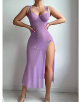 Person wearing a purple dress with floral details on a plain background