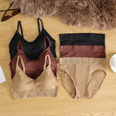 Set of women's underwear in black, brown, and beige on a wooden surface with a fur rug in the background.
