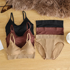 Set of women's underwear in black, brown, and beige on a wooden surface with a fur rug in the background.