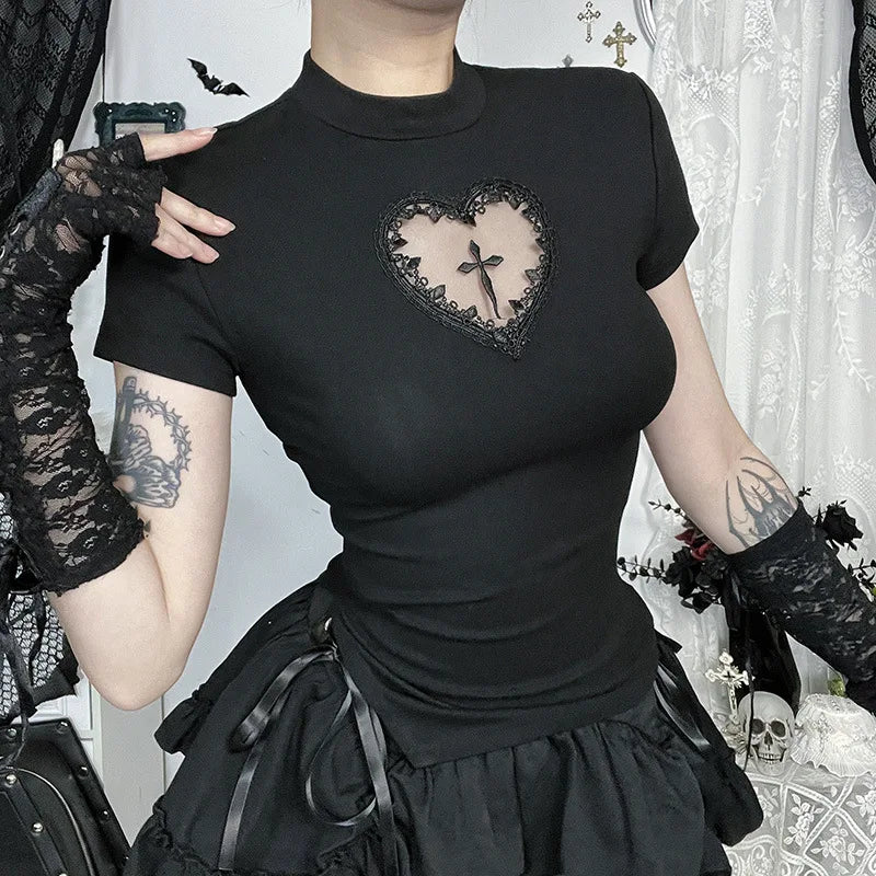 Person wearing a black t-shirt with a heart design and cross, standing in a decorative room.