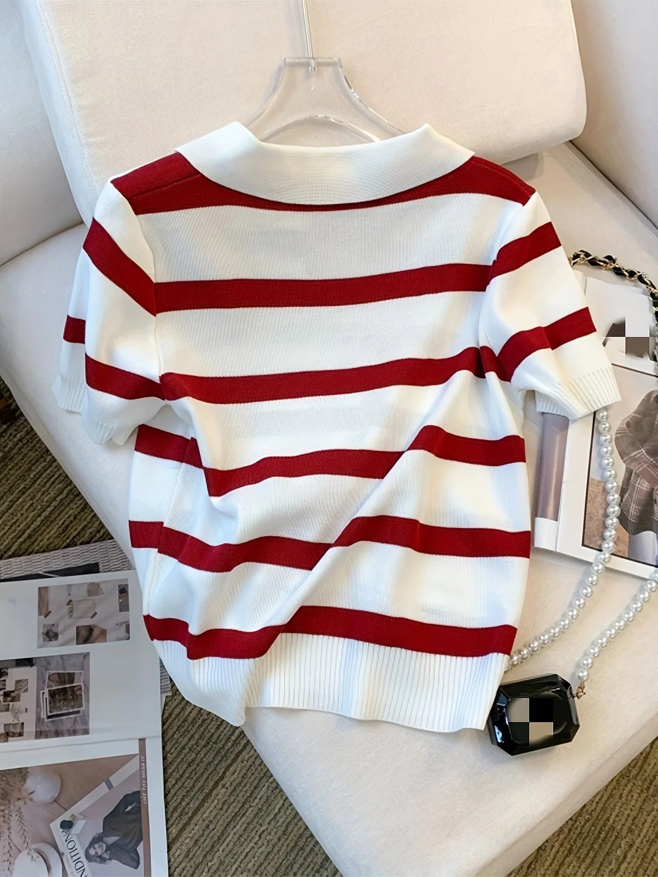Red and white striped sweater on a hanger against a neutral background