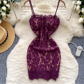 Purple lace dress on a hanger with decorative items on a fluffy white rug.