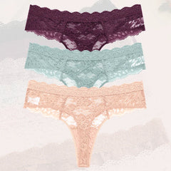 Three pairs of lace underwear in purple, green, and pink on a textured white background.