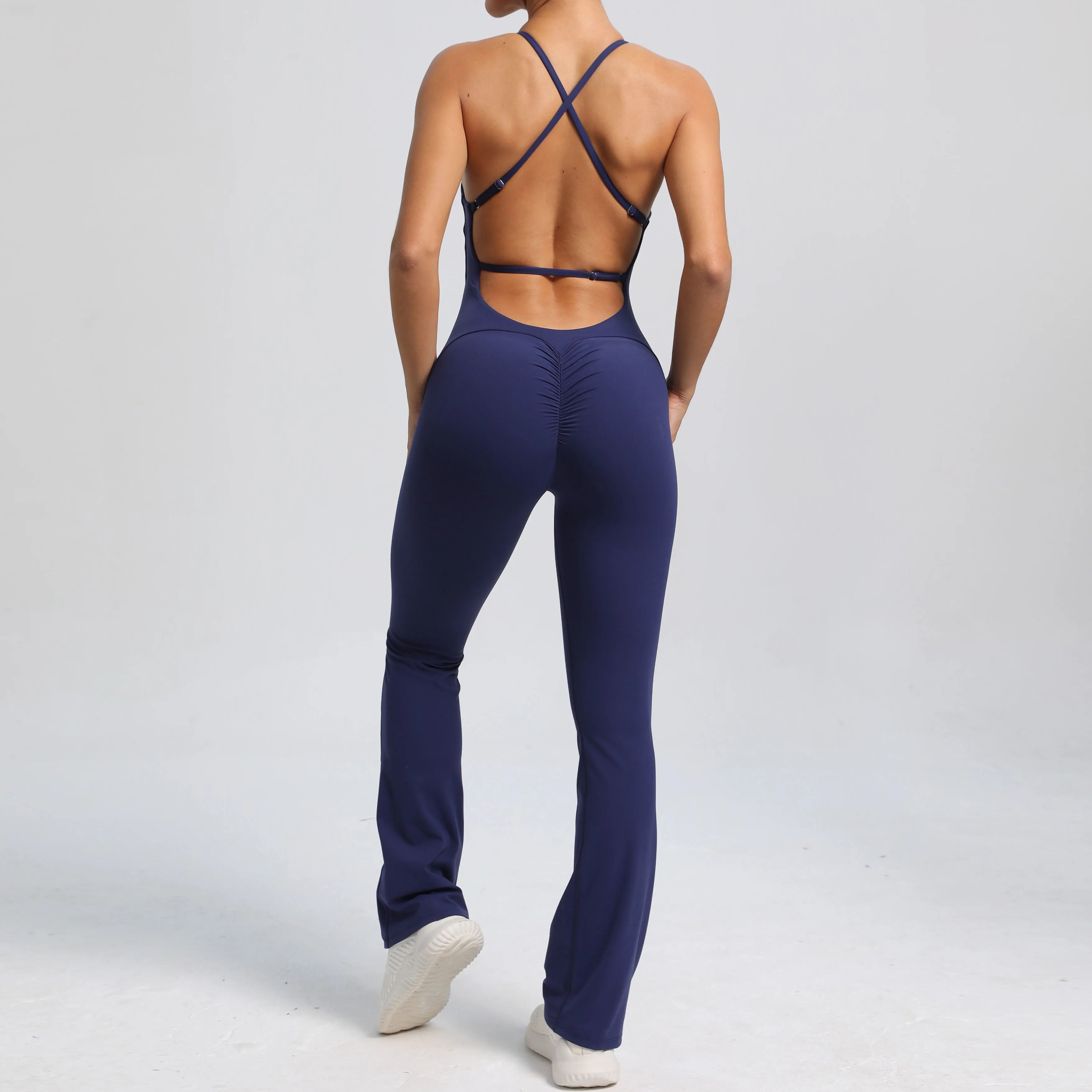 Person wearing a navy blue jumpsuit with criss-cross back design on a light gray background