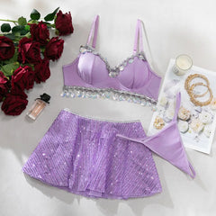Purple lingerie set with sequin details on a white surface with flowers and jewelry.