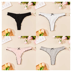 Four pairs of women's underwear in black, white, pink, and gray on a beige surface with flowers and cards.