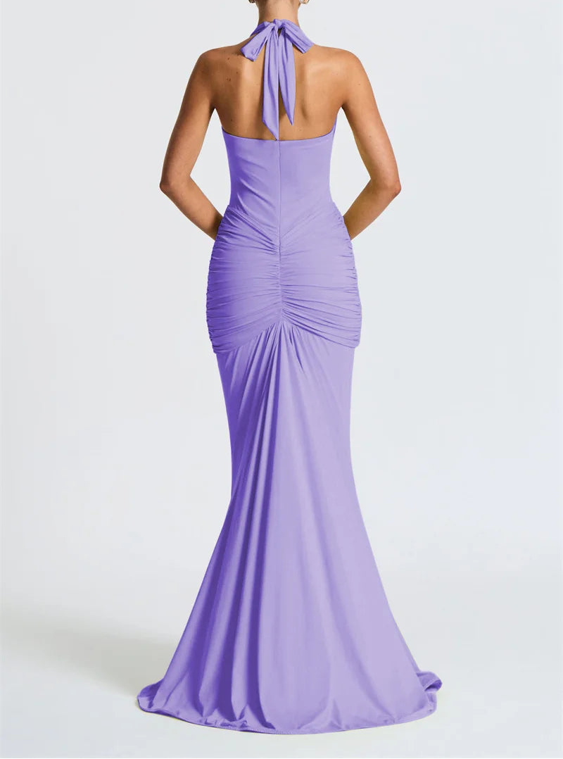 Woman wearing a long purple dress with a halter neck design on a white background