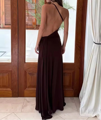 Woman wearing a long, dark brown dress with thin straps in an indoor setting.