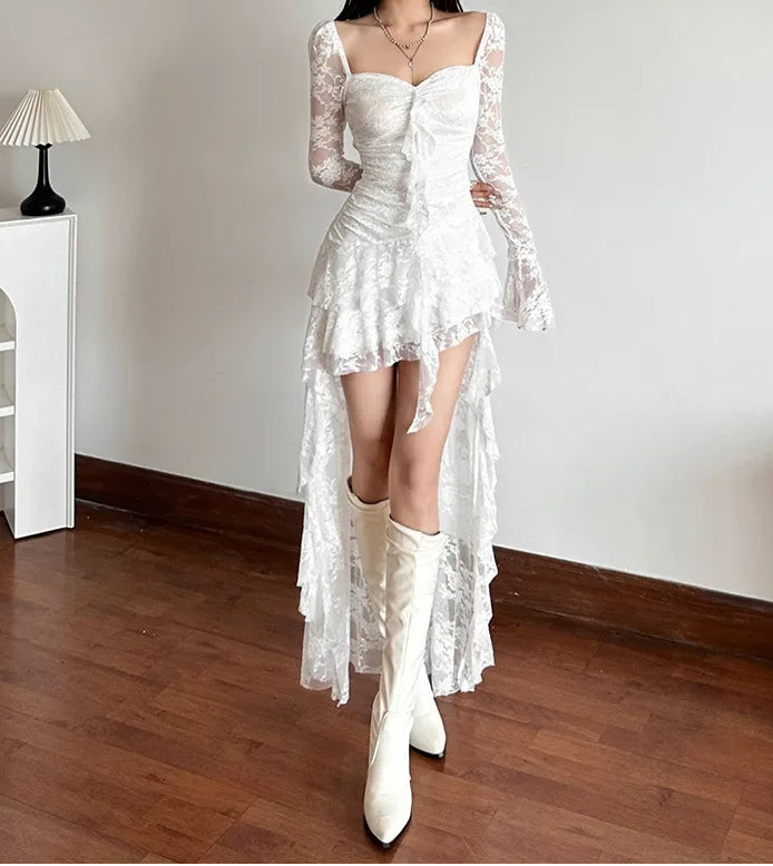 Woman wearing a white lace dress and boots in a room with wooden floor and white walls.
