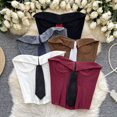 Five bow-tie neckties in different colors on a textured surface with floral decorations.