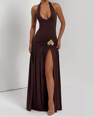 Woman wearing a brown halter neck dress with a gold embellishment on a white background