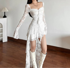 Woman wearing a white lace dress with long sleeves in an indoor setting.