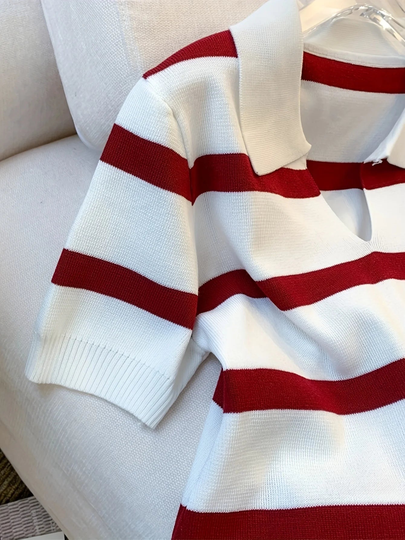 White sweater with red stripes on a light-colored couch