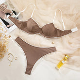 Brown ribbed bra and panties set on a light background with a bottle and jewelry.