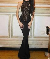Woman wearing a black lace evening gown in an elegant room.