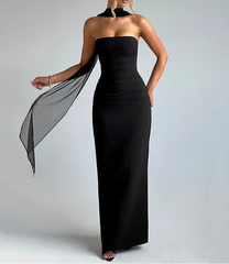 Woman wearing a black strapless gown with a sheer black capelet on a gray background