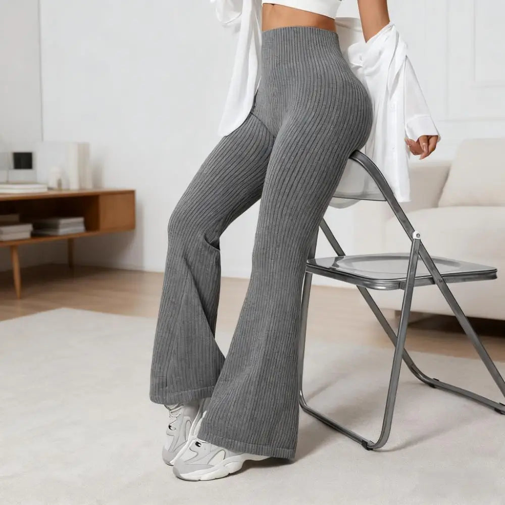 Person wearing gray ribbed pants sitting on a chair in a room.