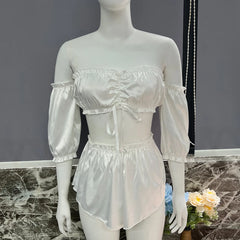 Mannequin wearing a white satin outfit with sheer sleeves against a gray background.