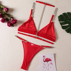 Red lingerie set with chains on a beige background with flowers and a card.