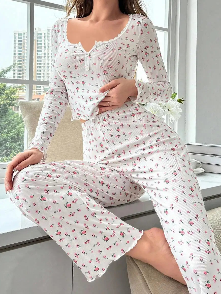 Woman wearing a floral pajama set sitting by a window with a cityscape view.