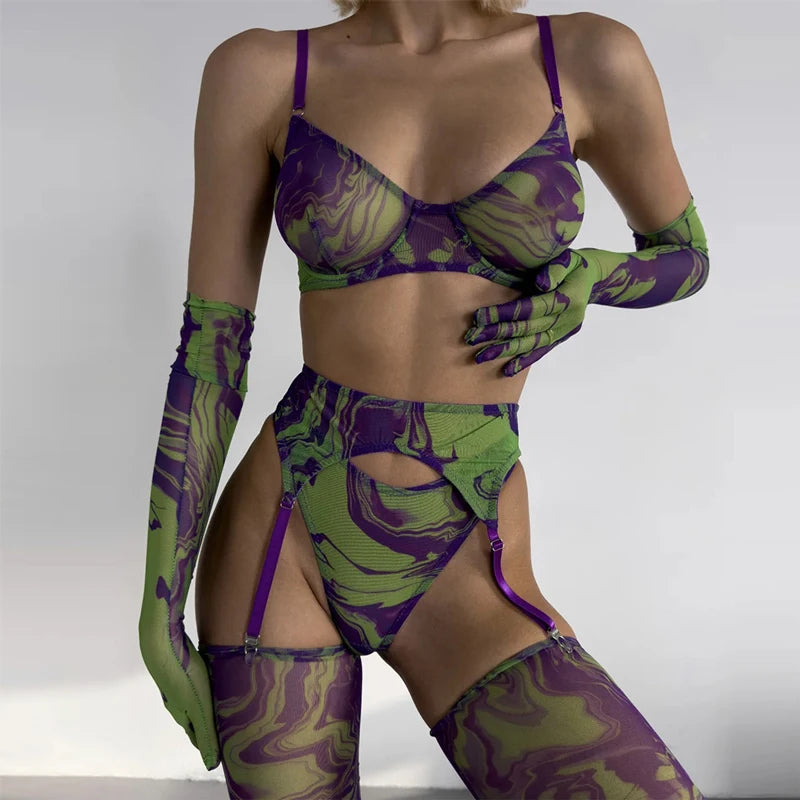 Person wearing a green and purple patterned lingerie set with matching gloves and stockings on a plain background.