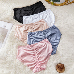 Set of women's underwear in black, white, pink, and blue on a textured surface.