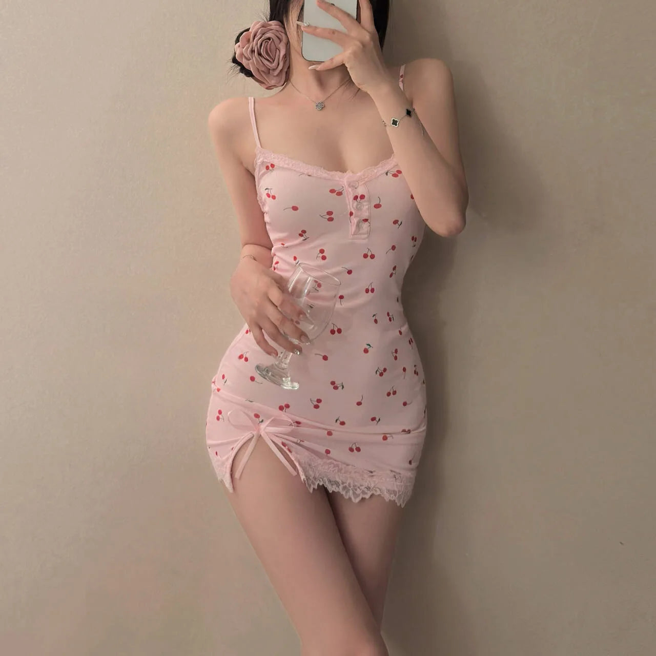 Person wearing a pink lace nightgown holding a glass against a plain background