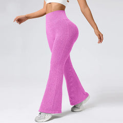 Person wearing bright pink ribbed knit pants on a plain background