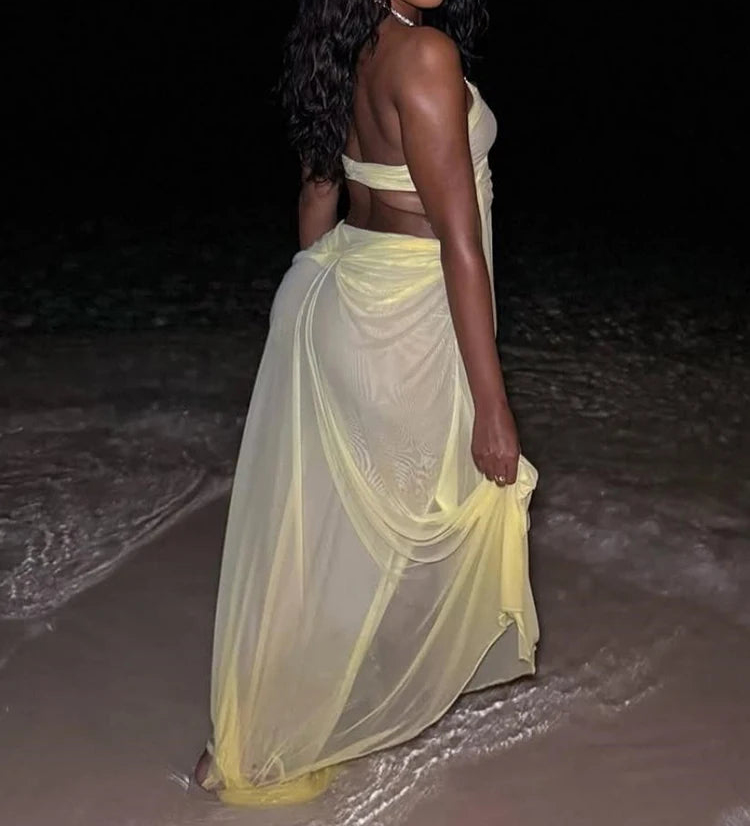 Woman in a yellow dress standing on a beach at night