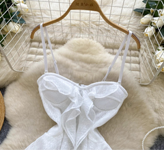 White lace top on a wooden hanger against a textured white background