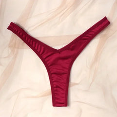 Red thong underwear on a light pink fabric background