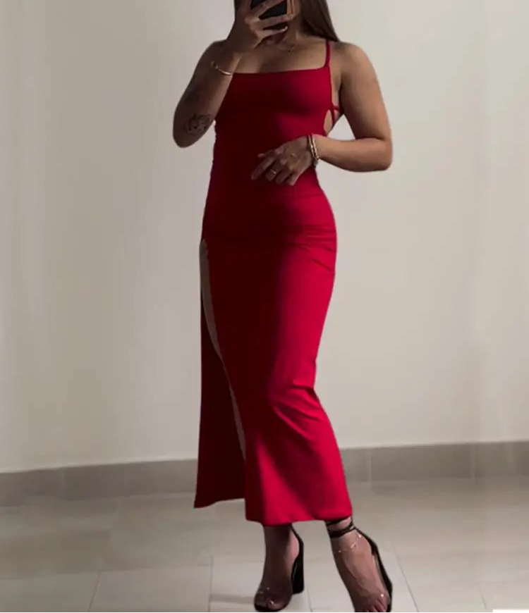 Person wearing a red dress with a slit, standing against a plain background.