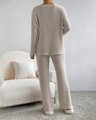 Person wearing a beige ribbed lounge set in a living room.